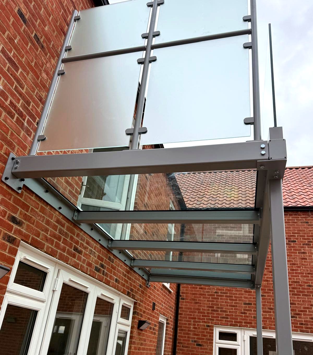 Underside of a light grey powder-coated steel balcony frame carrying walk-on floor glass, Rutland